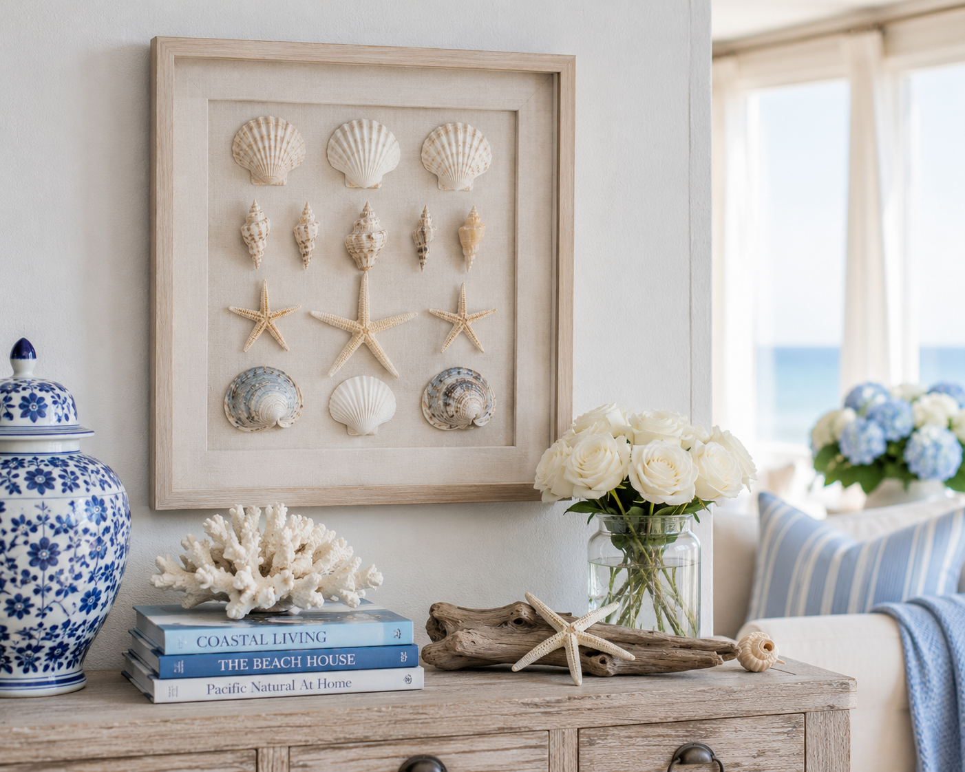 Framed seashell wall art displayed above coastal books, coral and flowers